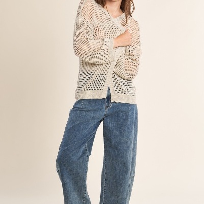 Mulher com camisola de malha bege, calças de ganga largas azuis e sandálias castanhas