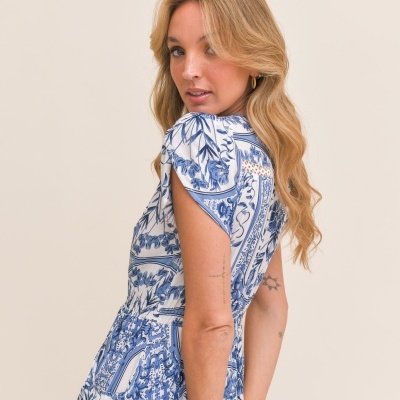 Mulher loira de vestido azul e branco estampado com padrão floral e geométrico