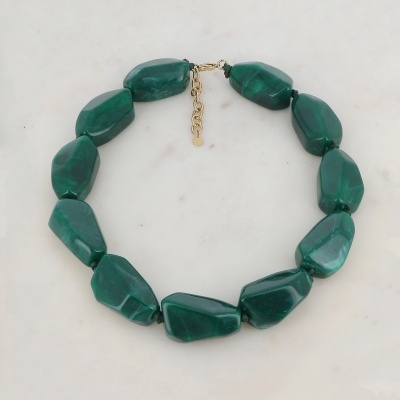 Colar de pedras verdes com fecho dourado sobre fundo branco marmoreado
