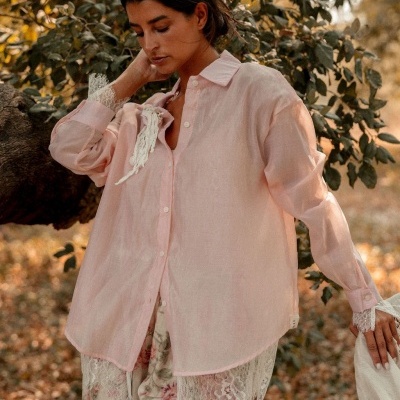 Mulher com camisola rosa claro e calças floridas com renda numa floresta outonal