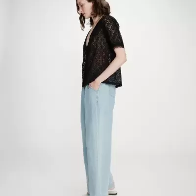 Blusa preta de renda transparente com calças de ganga e sapatos brancos
