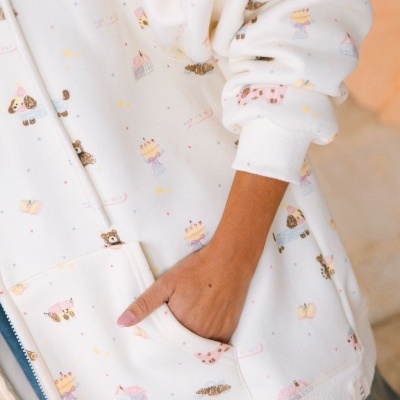 Casaco branco com padrão de desenhos infantis e bolso canguru