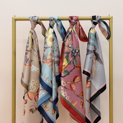 Quatro lenços florais coloridos pendurados numa barra amarela