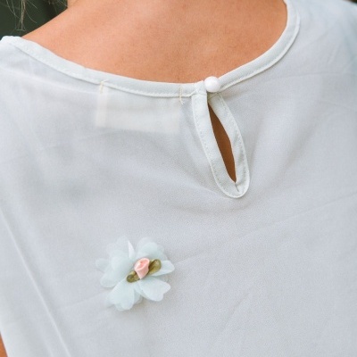 Blusa branca transparente com botão e flor decorativa no pescoço