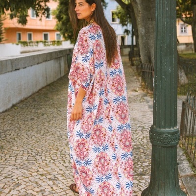 Vestido comprido padrão floral vermelho, azul e branco em calçada de pedra ao ar livre