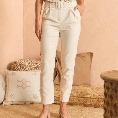 Calças compridas bege com cinto largo e sandálias douradas rasas.