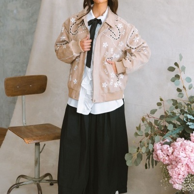 Casaco rosa claro bordado com flores brancas e punhos de malha.