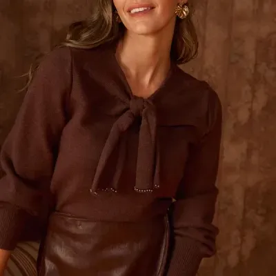 Mulher com camisola castanha de malha e saia em pele sintética castanha