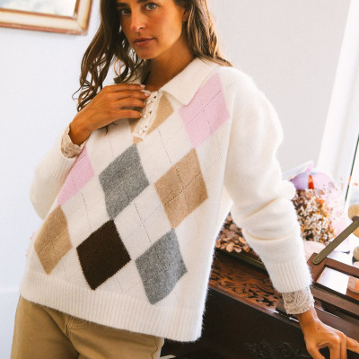 Mulher com camisola de malha branca com padrão argyle colorido encostada a um piano de madeira escura