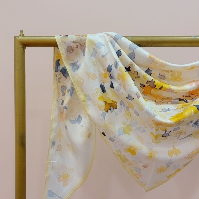 Lenço com padrão floral em tons pastel pendurado em estrutura dourada