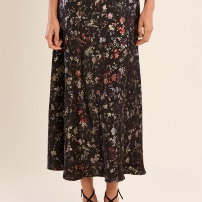 Saia midi preta com padrão floral colorido e sandálias pretas de tiras