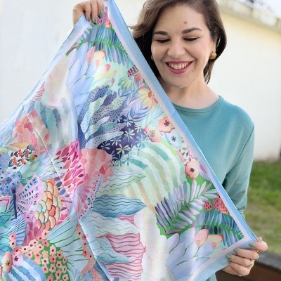 Mulher a segurar lenço colorido com padrão floral pastel em tons de azul e rosa.
