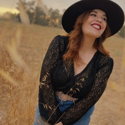 Mulher com chapéu preto e blusa de renda preta no campo