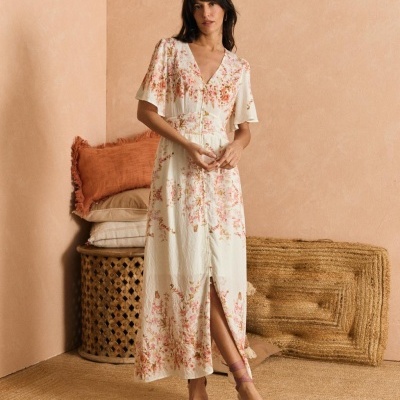 Vestido longo feminino floral com espadrilles rosa num cenário de decoração em tons terra