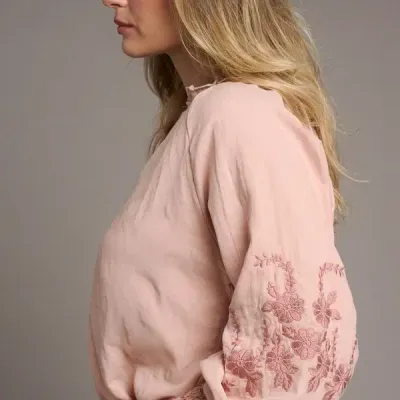 Blusa feminina cor-de-rosa com bordados florais na manga e punho elástico