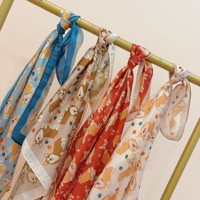 Lenços com padrão de cães Corgi em várias cores pendurados num suporte amarelo.