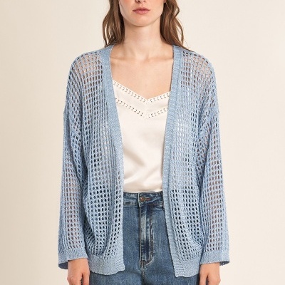 Mulher com cárdigan azul de malha aberta, top branco e calças de ganga largas