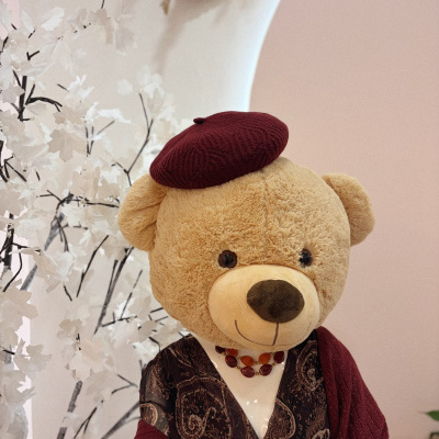Urso de peluche vestido com boina bordô e vestido padrão castanho