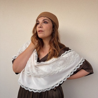Mulher com vestido castanho e lenço branco bordado com touca castanha