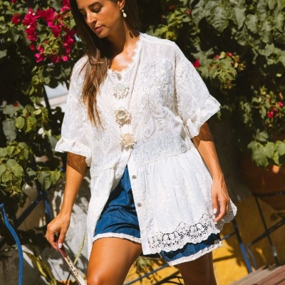 Camisa branca bordada e calções de ganga em ambiente exterior com plantas