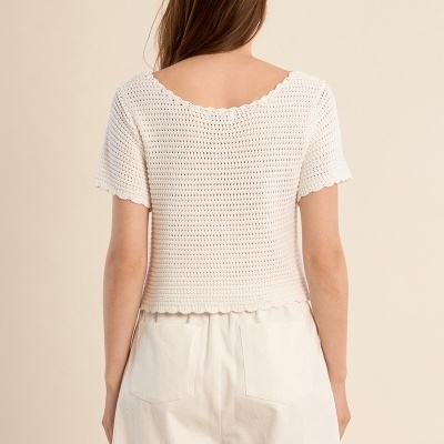 Blusa branca de malha cropped vista de costas com calções brancos.