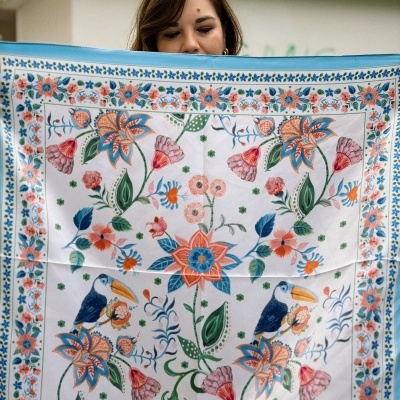 Lenço branco com padrão floral colorido e toucans segurado por mulher