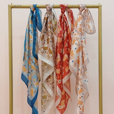 Lenços com padrão de cães corgi pendurados num cabide amarelo