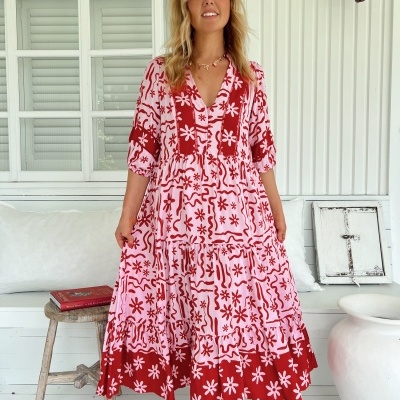 Vestido rosa com padrão vermelho, usado por mulher com sapatilhas brancas, ambiente interior branco