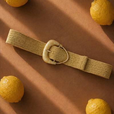 Cinto tecido bege com fivela marfim numa mesa castanha com limões amarelos.