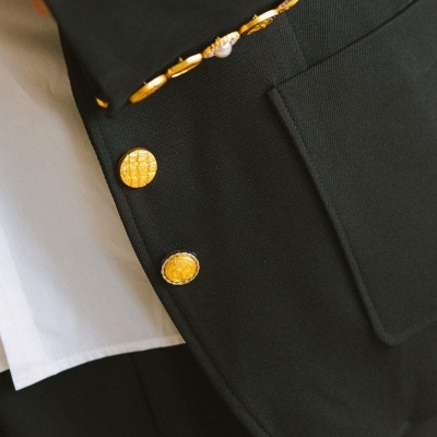 Casaco preto com botões dourados e camisa branca