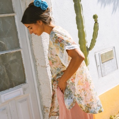 Mulher com blusa floral e presilha azul com flores.
