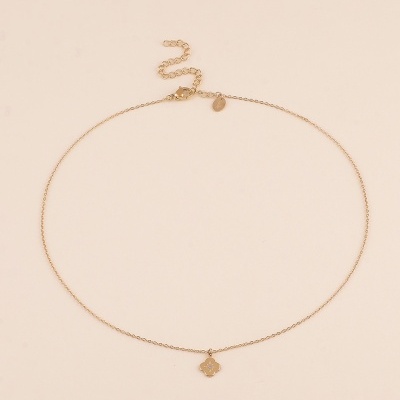 Colar dourado com pendente de flor e cristais em fundo neutro