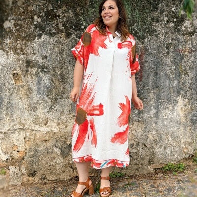 Vestido midi branco com floresta vermelha e castanha usado por mulher perto de parede de pedra