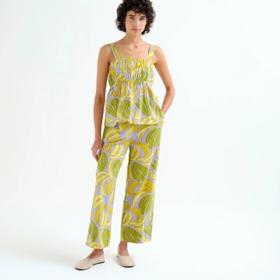 Conjunto de pijama feminino com padrão de bananas amarelas e verdes sob fundo lilás.