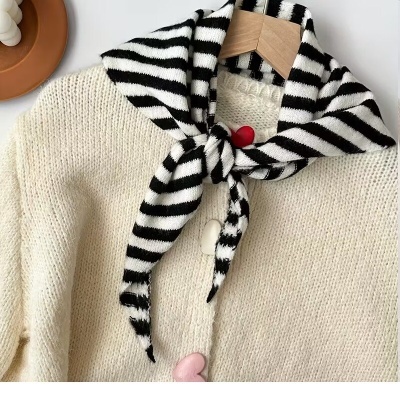 Casaco creme com botões de coração e cachecol riscado preto e branco.