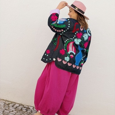 Casaco jeans bordado colorido, calças rosa largas, sandálias vermelhas e chapéu rosa claro com broche.
