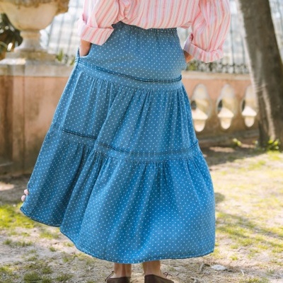 saia azul com bolinhas brancas e camisa às riscas cor-de-rosa vista de trás em ambiente exterior
