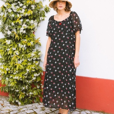 Vestido comprido preto com flores usadas por mulher com chapéu de palha