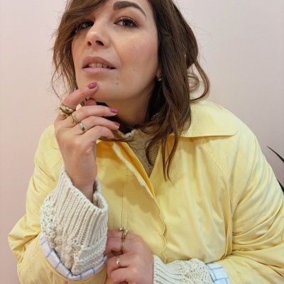 Mulher com casaco amarelo e camisola creme com punhos tricotados