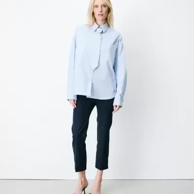 Mulher com camisa azul clara às riscas finas brancas e gravata, calças pretas às riscas brancas e sandálias de salto alto