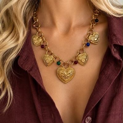 Colar dourado com corações e pedras coloridas junto ao pescoço de mulher