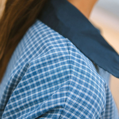 Camisa padrão xadrez azul e branco com gola azul escura vista de perto