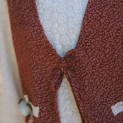 Casaco vermelho com padrão floral e laço frontal sobre blusa branca texturizada