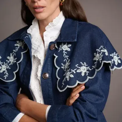Casaco denim azul escuro com bordados brancos florais e botões castanhos