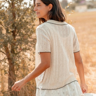 Camisa feminina de malha bege com detalhes pretos e blusa branca bordada