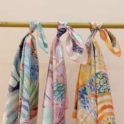 Três lenços florais coloridos pendurados num varão amarelo