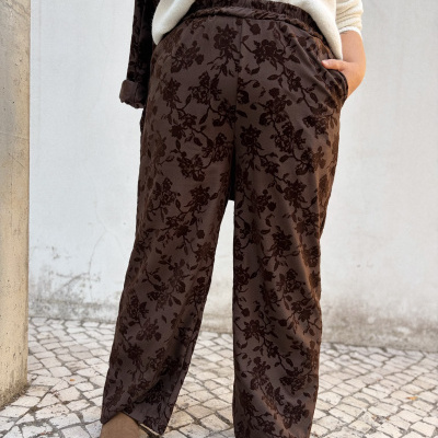 Calças castanhas com padrão floral em relevo e botas castanhas