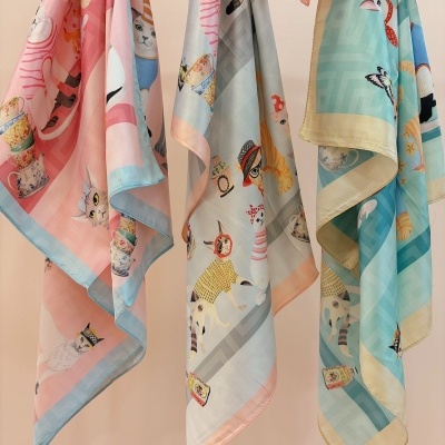 Três lenços coloridos com padrão de gatos pendurados