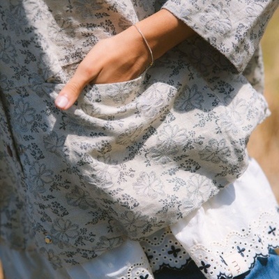 Blusa cinza com padrão floral e detalhe branco bordado com mão no bolso e etiqueta maîtè