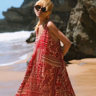 Vestido vermelho com padrão patchwork bege usado na praia com óculos escuros